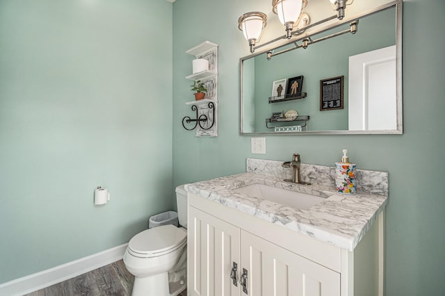 7379 Wimpole Dr NE, Belding, MI 48809 - half bath featuring wood finished floors, toilet, vanity, baseboards, and a chandelier