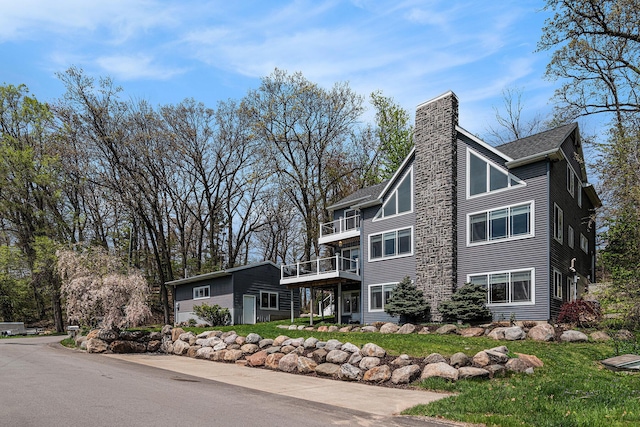 7379 Wimpole Dr NE, Belding, MI 48809 - view of property exterior with a balcony, a chimney, and roof with shingles