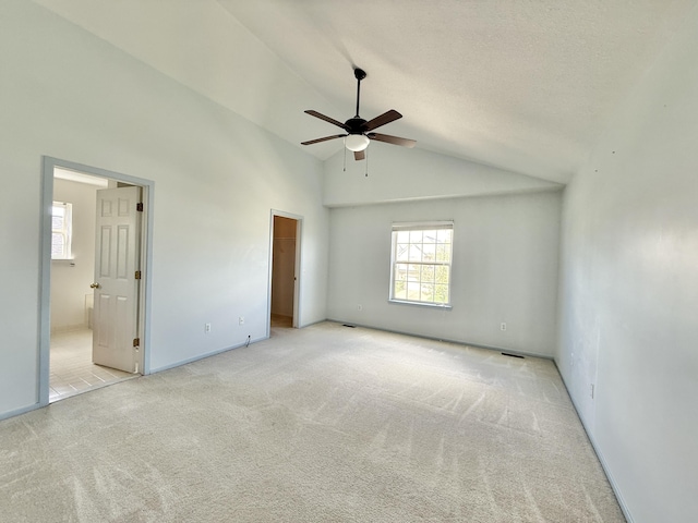 unfurnished bedroom featuring multiple windows, carpet floors, vaulted ceiling, a walk in closet, and connected bathroom