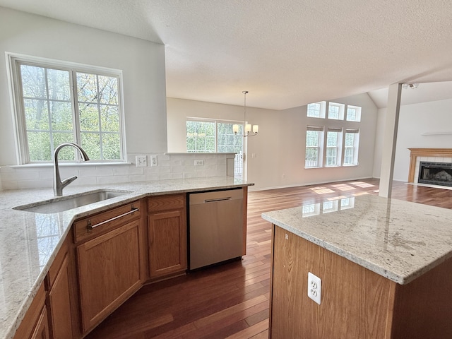 kitchen with stainless steel dishwasher, wood finished floors, plenty of natural light, a textured ceiling, and vaulted ceiling