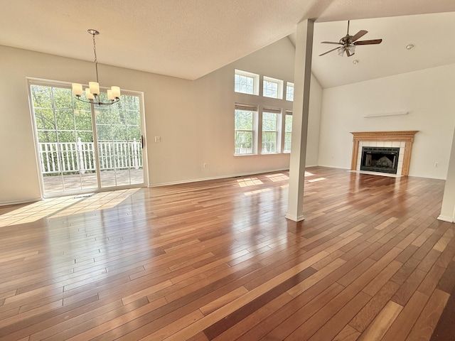 unfurnished living room featuring healthy amount of natural light, a fireplace, wood finished floors, a ceiling fan, and high vaulted ceiling