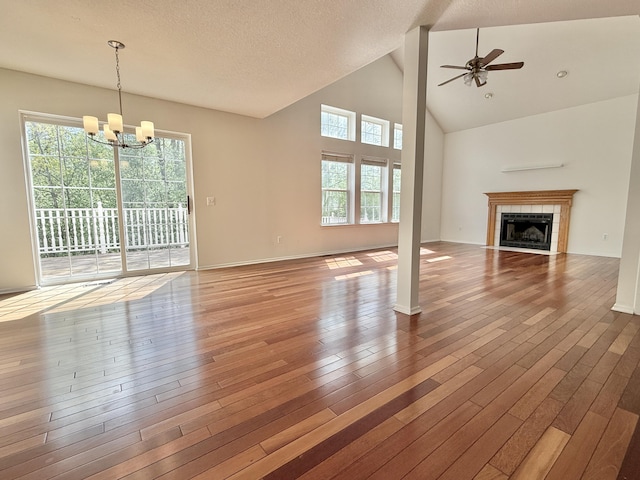 unfurnished living room with a chandelier, ceiling fan, wood finished floors, a fireplace, and high vaulted ceiling