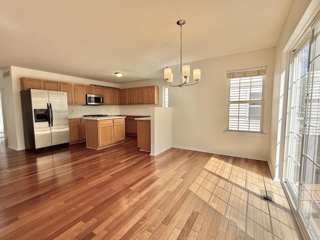 kitchen with appliances with stainless steel finishes, dark wood-style flooring, a chandelier, light countertops, and open floor plan