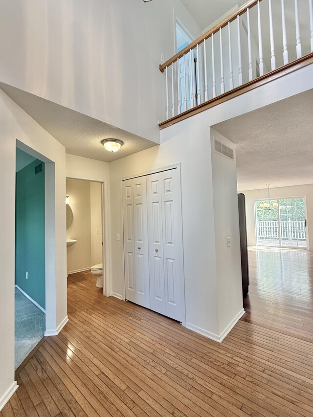 foyer entrance with wood-type flooring, baseboards, a chandelier, and a high ceiling