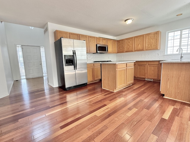 kitchen featuring stainless steel appliances, wood-type flooring, decorative backsplash, and light countertops
