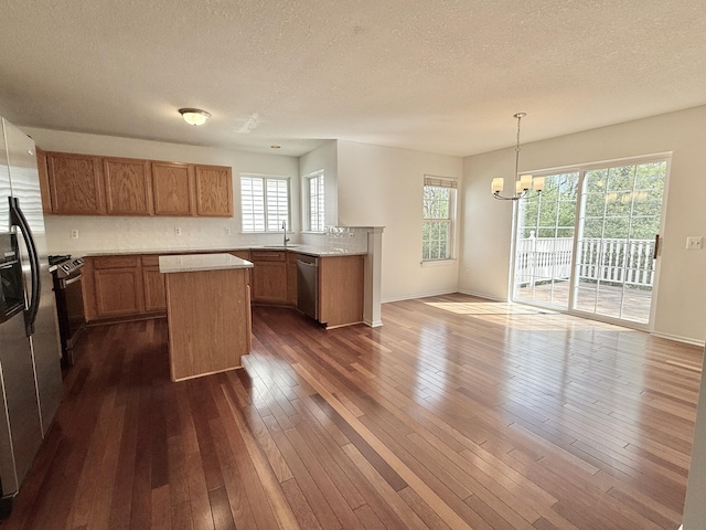 kitchen featuring appliances with stainless steel finishes, a chandelier, a textured ceiling, light countertops, and a sink