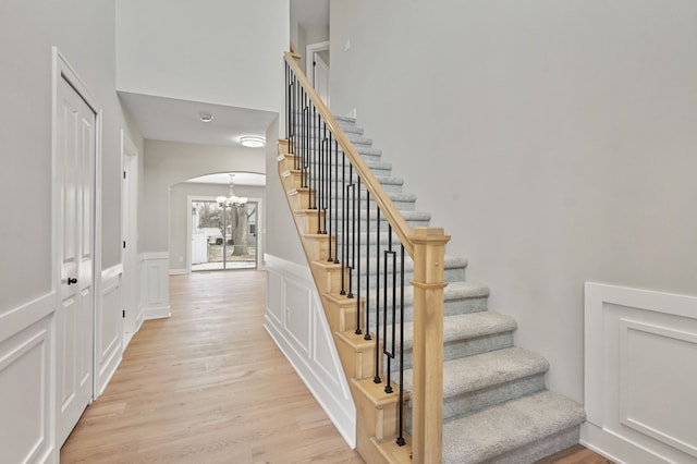 53302 Zachary Dr, Chesterfield, MI 48047 - stairs featuring wood finished floors, a chandelier, arched walkways, a wainscoted wall, and a decorative wall