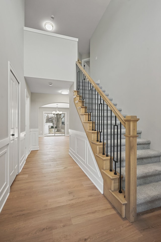 53302 Zachary Dr, Chesterfield, MI 48047 - stairway featuring a chandelier, a decorative wall, wood finished floors, a high ceiling, and wainscoting