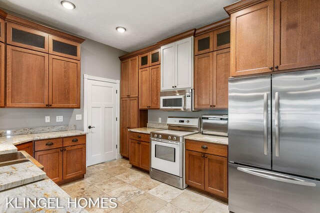 223 E Savidge St, Spring Lake, MI 49456 - kitchen with stainless steel fridge, range with electric stovetop, brown cabinets, light stone countertops, and glass insert cabinets