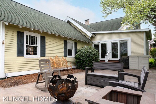223 E Savidge St, Spring Lake, MI 49456 - back of property featuring a fire pit, a patio area, roof with shingles, a chimney, and french doors