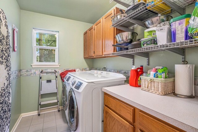 laundry room with independent washer and dryer, cabinet space, light tile patterned flooring, and baseboards