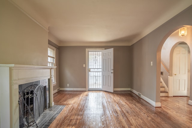 20121 Briarcliff Rd, Detroit, MI 48221 - unfurnished living room with arched walkways, wood finished floors, stairs, baseboards, and a fireplace