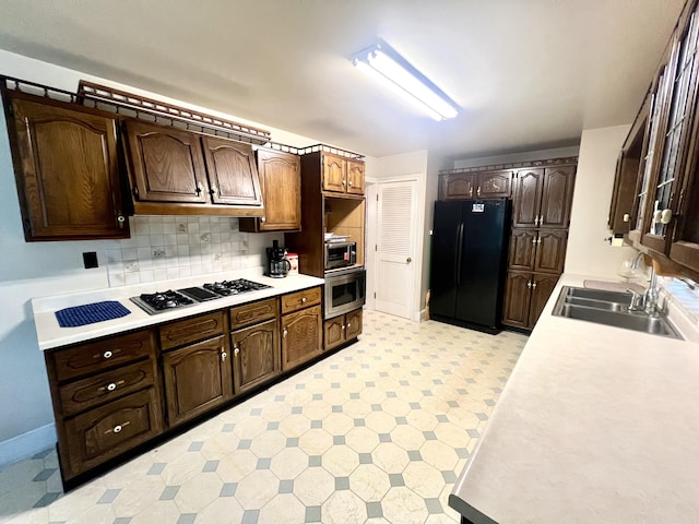 103 Lukesport Dr, Quincy, MI 49082 - kitchen with freestanding refrigerator, a sink, gas stovetop, light countertops, and dark brown cabinets
