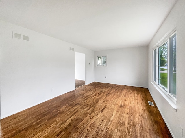 unfurnished room with dark wood-style flooring, plenty of natural light, and baseboards