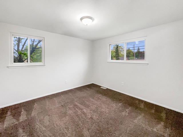 unfurnished room featuring dark colored carpet and baseboards