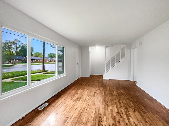 unfurnished living room featuring hardwood / wood-style flooring, baseboards, and stairs