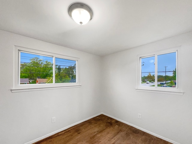 spare room with baseboards and dark wood-style flooring