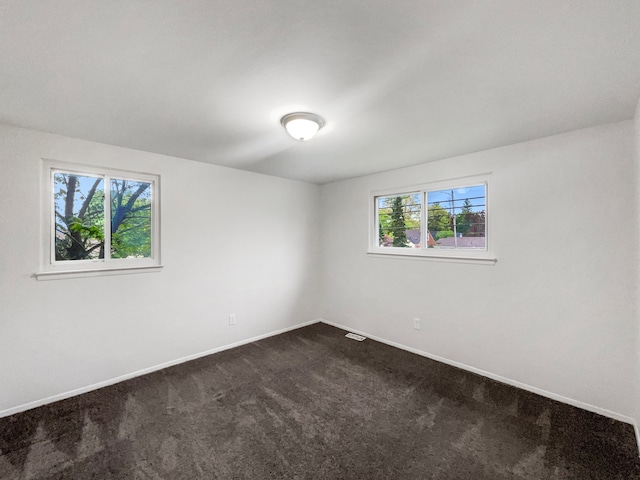empty room with dark colored carpet and baseboards