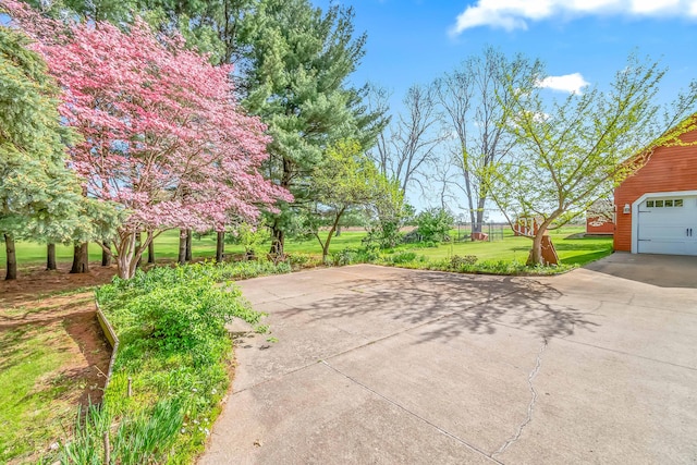 view of grassy yard featuring concrete driveway and a garage