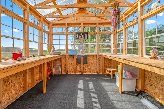 unfurnished sunroom with lofted ceiling, carpet, and a workshop area