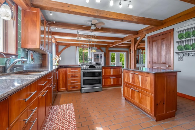 kitchen featuring range with two ovens, a sink, a peninsula, brown cabinets, and dark stone counters