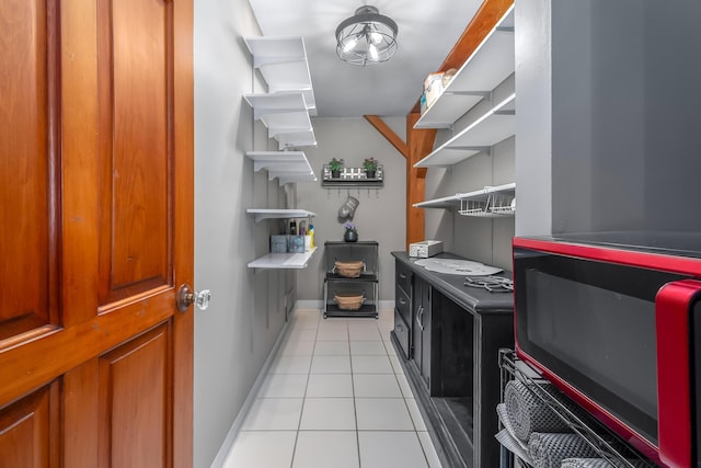 clothes washing area with light tile patterned floors and baseboards