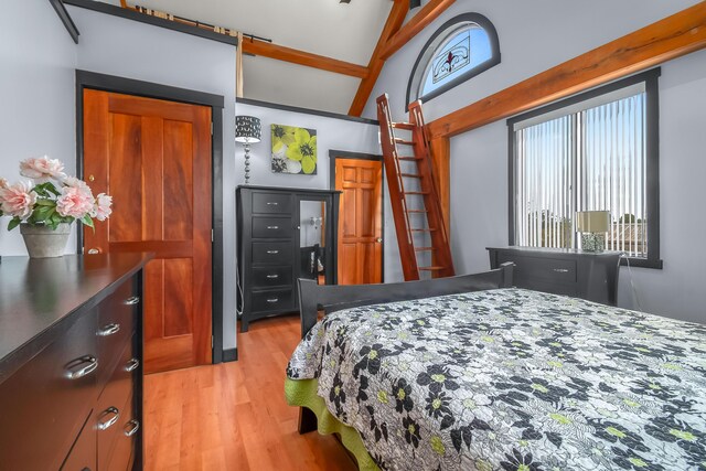 bedroom with light wood finished floors and lofted ceiling