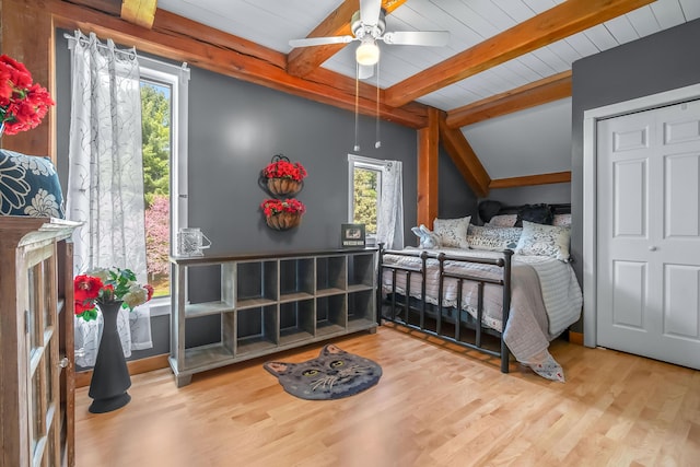 bedroom with beamed ceiling and wood finished floors
