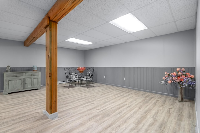 finished basement featuring wood finished floors, wainscoting, and a paneled ceiling