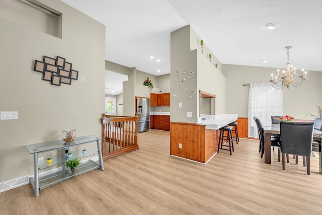 4953 Clintonville Rd, Clarkston, MI 48346 - kitchen featuring high quality fridge, light wood finished floors, a chandelier, a breakfast bar area, and brown cabinetry
