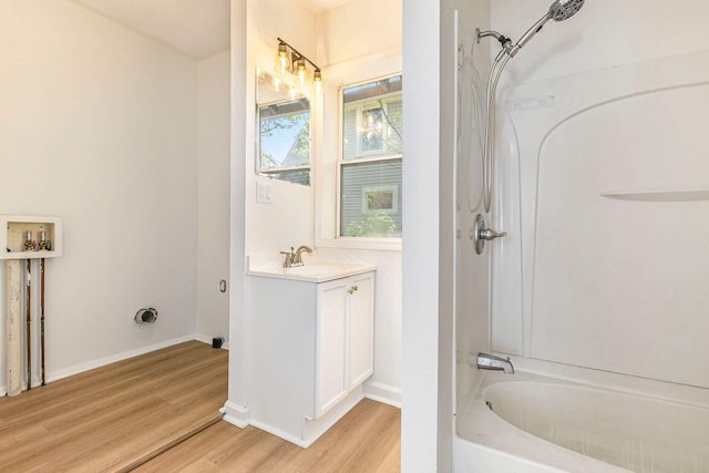 full bath with wood finished floors,  shower combination, baseboards, and vanity