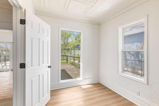 entryway featuring light wood-style floors, an ornate ceiling, and baseboards