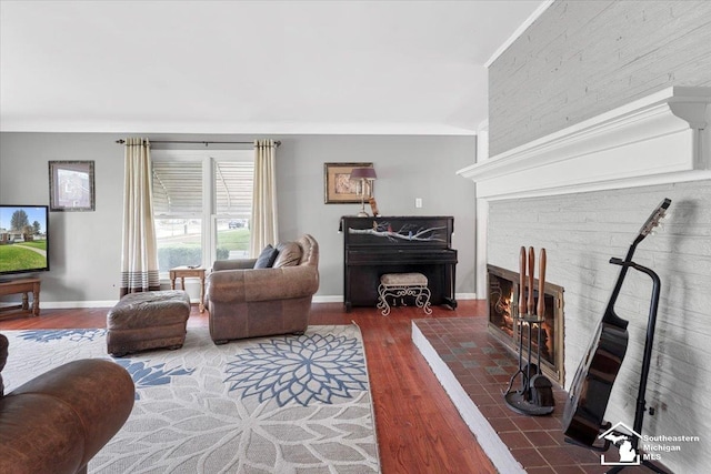 living room featuring wood finished floors, a brick fireplace, and baseboards