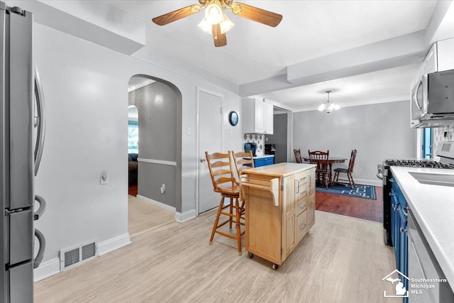 kitchen with stainless steel appliances, light wood-style floors, ceiling fan, a center island, and light countertops
