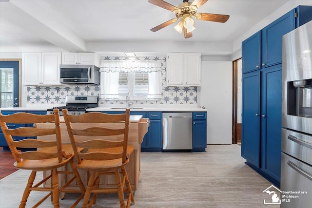 kitchen with appliances with stainless steel finishes, blue cabinets, a sink, and tasteful backsplash