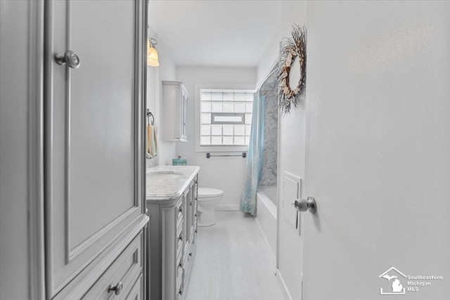 full bathroom with toilet, vanity, shower / bath combo, and baseboards