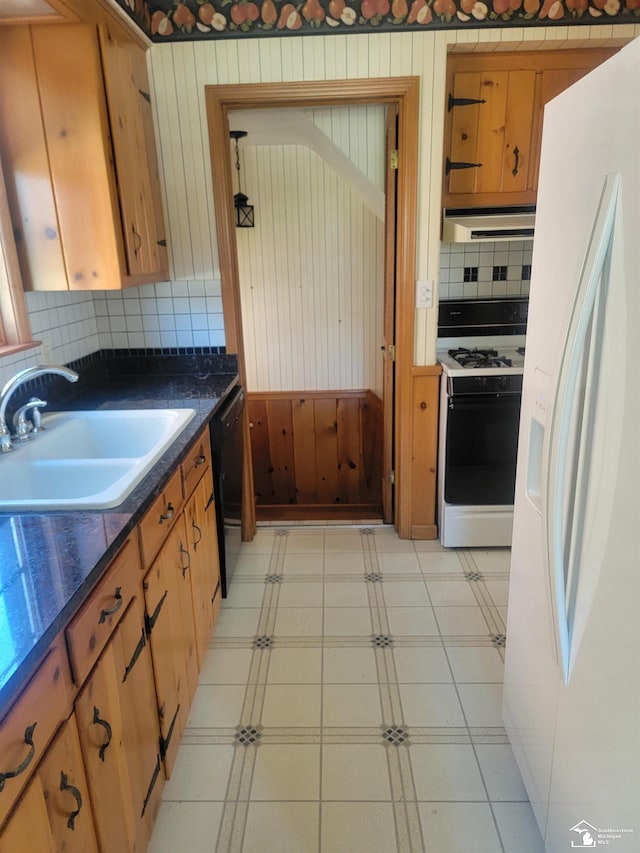 kitchen with white refrigerator with ice dispenser, range with gas cooktop, a sink, dishwasher, and decorative backsplash
