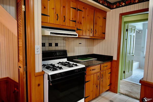 330 Devonshire St, Dearborn, MI 48124 - kitchen featuring gas range, under cabinet range hood, decorative backsplash, dark countertops, and brown cabinetry