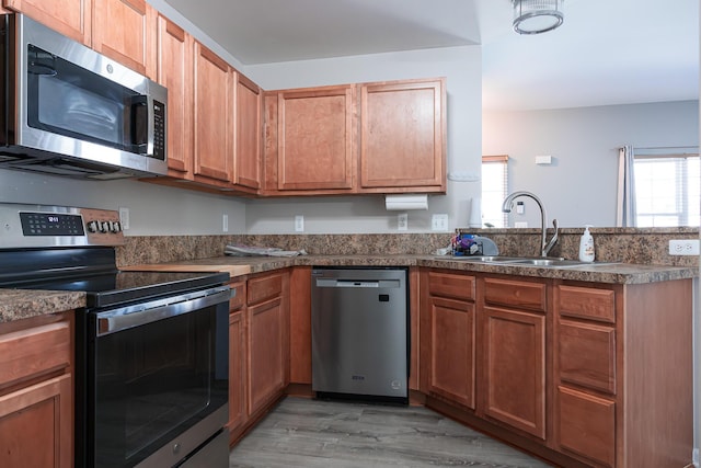 3050 Cloverly Ln, Ann Arbor, MI 48108 - kitchen featuring appliances with stainless steel finishes, a sink, a peninsula, light wood finished floors, and dark countertops