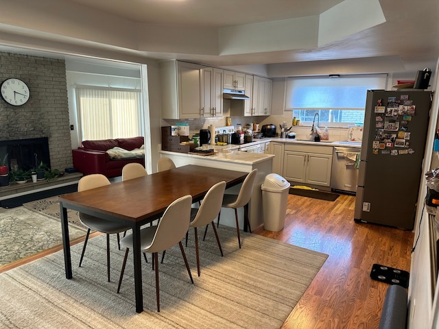 dining space featuring healthy amount of natural light, light wood-style flooring, and a brick fireplace