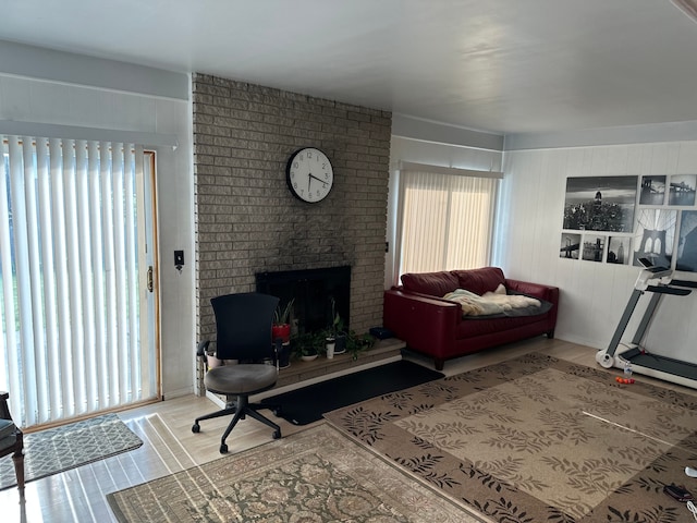 living room featuring wood finished floors, healthy amount of natural light, and a brick fireplace