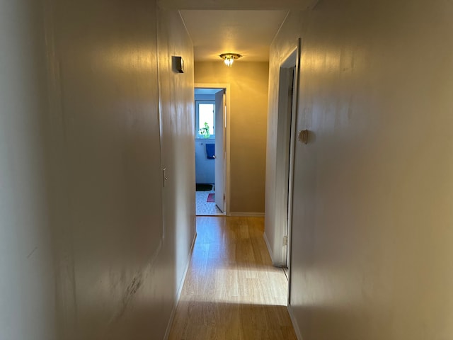hall with light wood-type flooring and baseboards