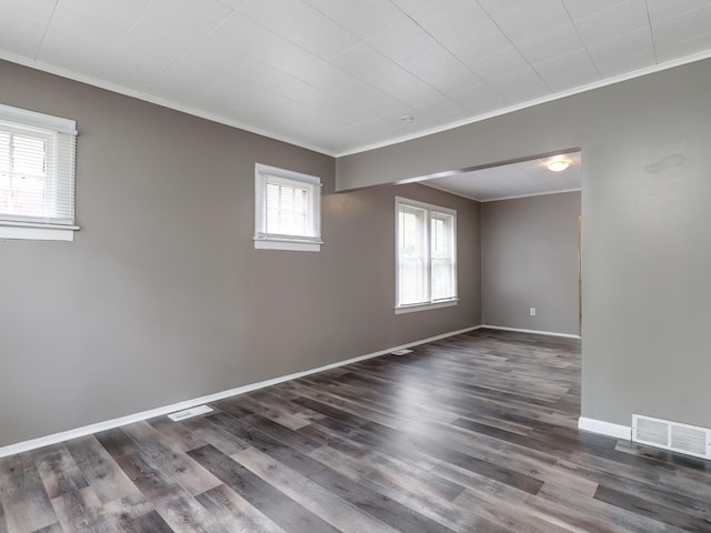 empty room featuring ornamental molding, dark wood-style floors, and baseboards