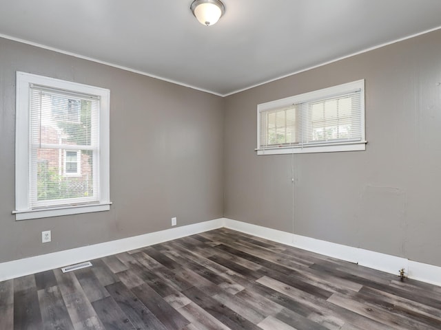 spare room with ornamental molding, plenty of natural light, dark wood finished floors, and baseboards