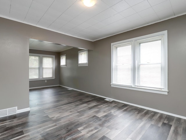 empty room featuring ornamental molding, wood finished floors, and baseboards
