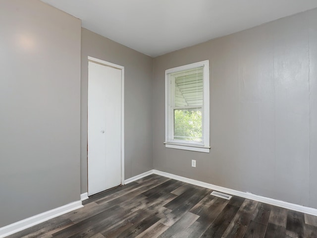 unfurnished room with dark wood finished floors and baseboards