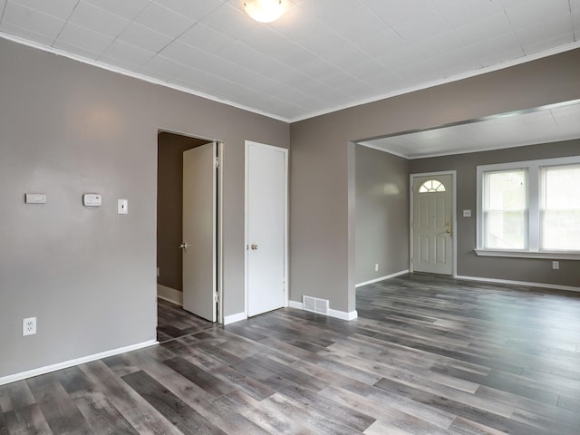 unfurnished living room featuring crown molding, wood finished floors, and baseboards