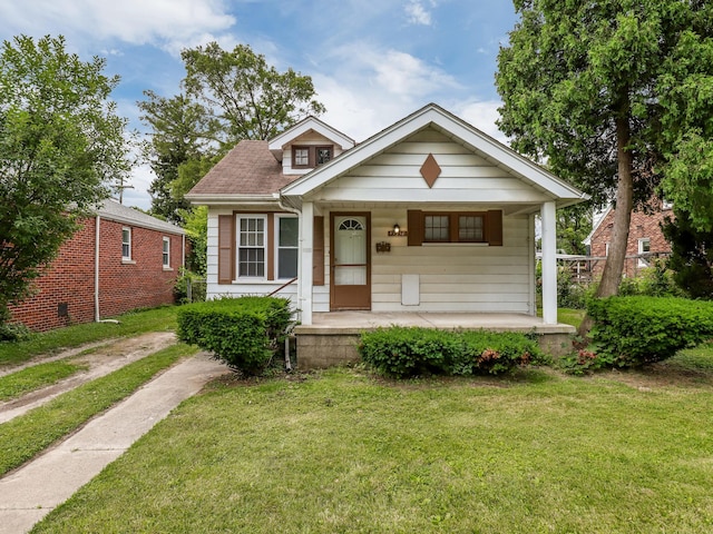 bungalow featuring covered porch and a front yard