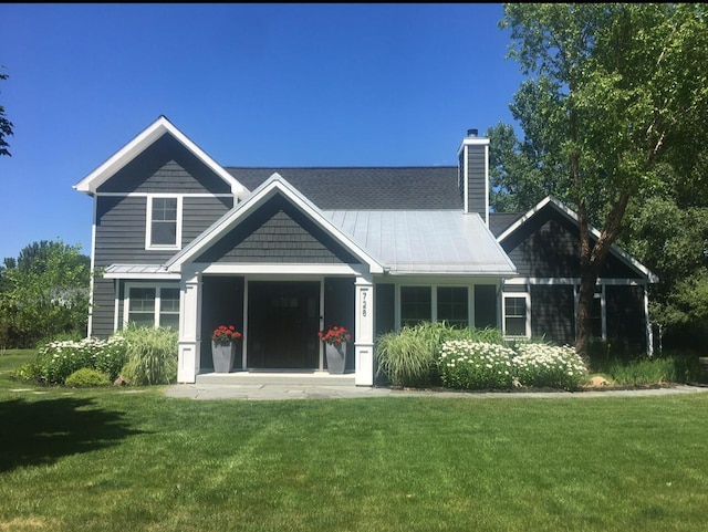 rear view of property with a yard, a standing seam roof, and a chimney