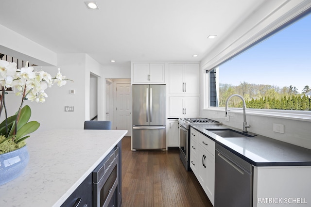 kitchen featuring appliances with stainless steel finishes, a sink, white cabinets, dark wood-style floors, and recessed lighting